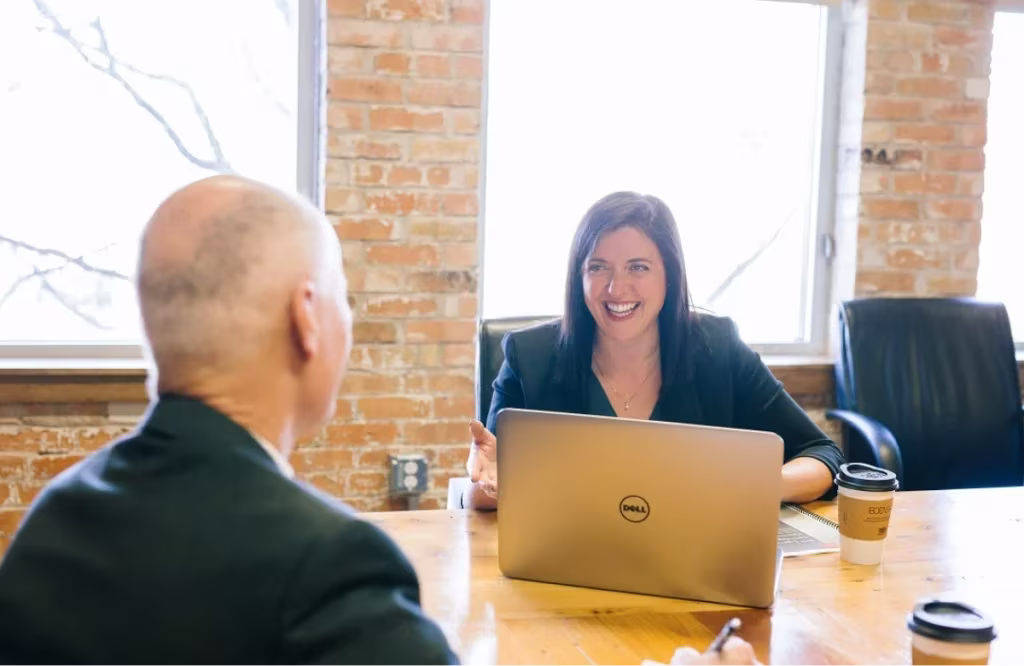 two people in a meeting room talking and smilling