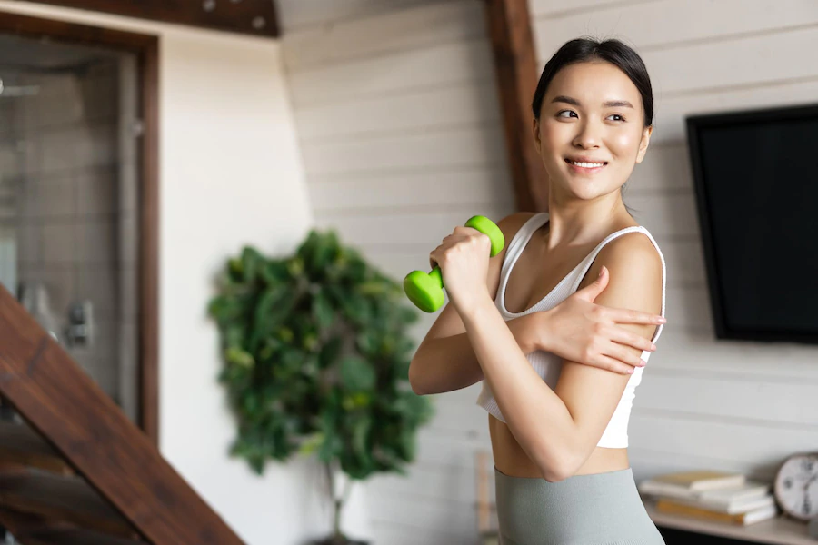 active healthy asian girl with fit body doing fitness exercises home lifting dumbbells benefits of a plant based diet